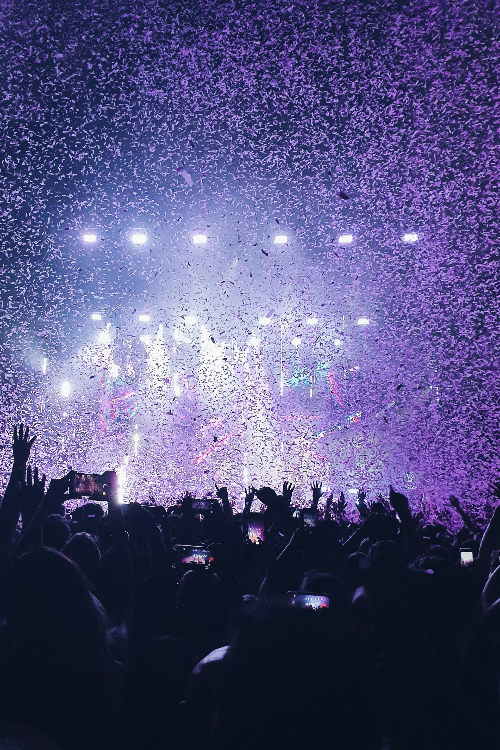 A concert crowd under falling confetti and stage lights
