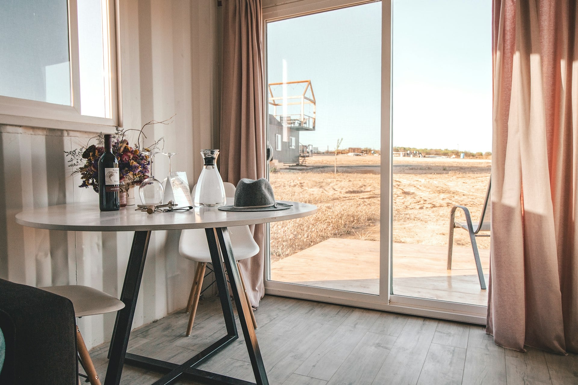 A glass of wine on a table beside a bright window